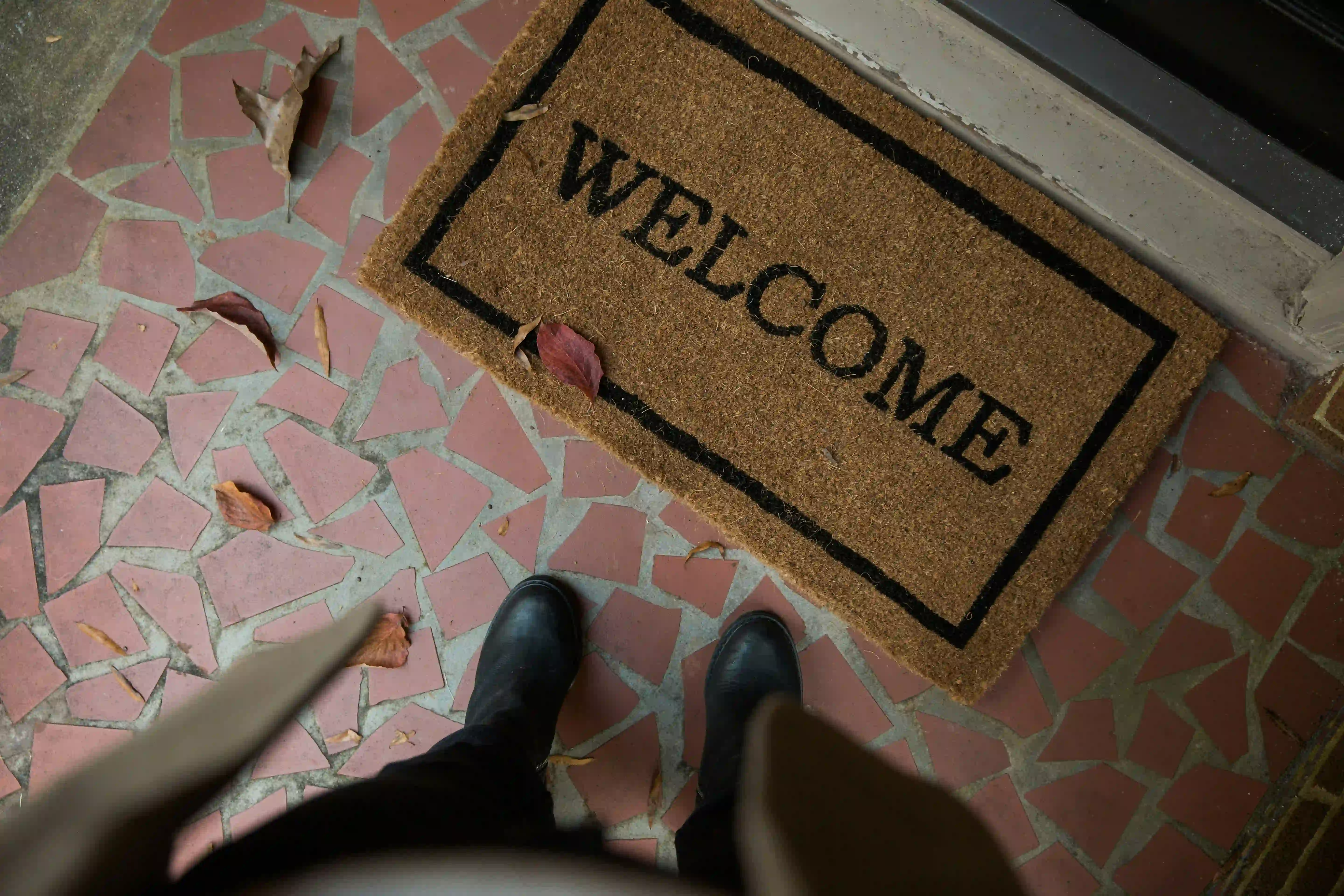 A person standing in front of a doormat that says 'Welcome'