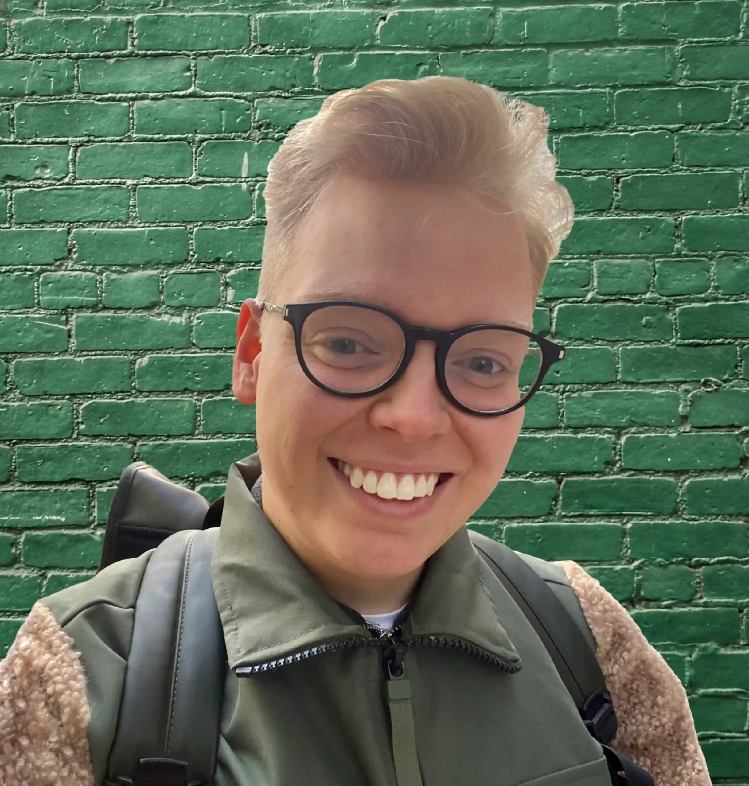 The top half of Arvid Berndtsson in front of a green brick wall.