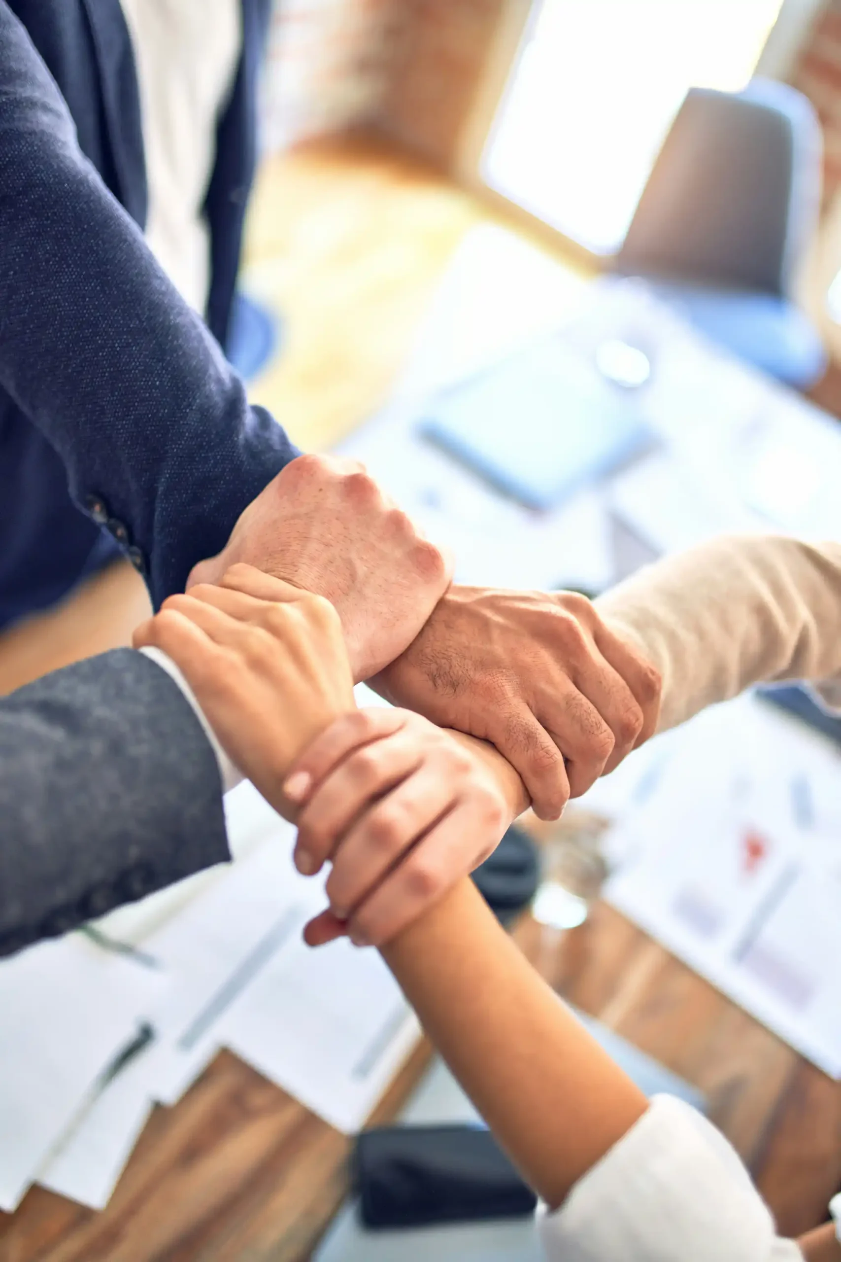 Four people holding each other's arms to show connection and teamwork.